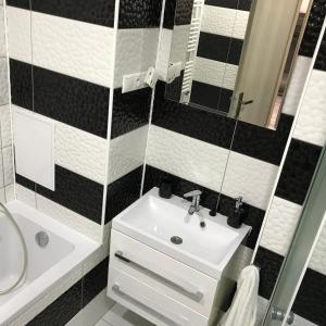 a black and white bathroom with a sink and a mirror at Apartmán v úplnom centre in Vranov nad Topľou