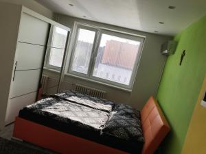 a small bedroom with a bed and two windows at Apartmán v úplnom centre in Vranov nad Topľou