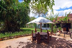 una mesa y sillas bajo una sombrilla en un patio en Mediterraneo Boutique Hotel, en Dar es Salaam