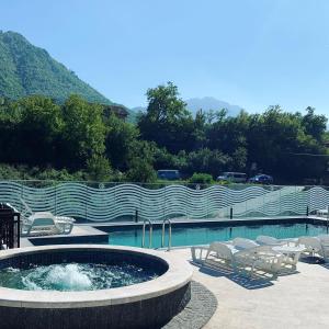 een zwembad met een hot tub, stoelen en een hek bij Hotel Novalić Konjic in Konjic