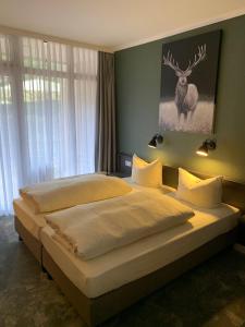 a bedroom with two beds and a deer painting on the wall at Waldhotel Riesebusch in Bad Schwartau