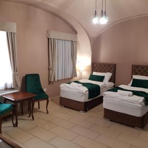 een hotelkamer met 2 bedden en een tafel en stoelen bij Régi Posta Étterem és Fogadó in Debrecen