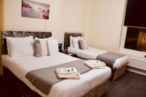 two beds in a hotel room with towels on them at The New Alexandra Hotel in Llandudno