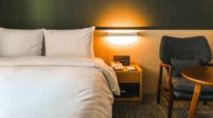 a hotel room with a bed and a chair and a table at ON City Hotel in Cheonan