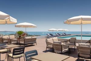 eine Terrasse mit Tischen und Stühlen sowie einem Pool in der Unterkunft H10 Imperial Tarraco 4 Sup in Tarragona