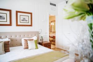 um quarto com uma cama com lençóis brancos e almofadas em Grand Hotel Terme Sirmione em Sirmione