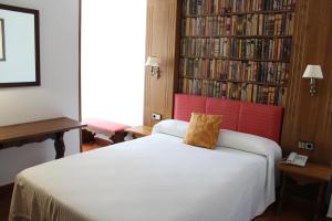 a bedroom with a bed and a book shelf with books at Hotel El Bedel in Alcalá de Henares