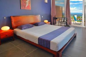 a bedroom with a bed and a balcony at Hôtel Villa Les Orchidées in Ambatoloaka