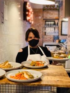 Una mujer con una máscara detrás de un mostrador con platos de comida en ApartHostel Warszawa, en Varsovia