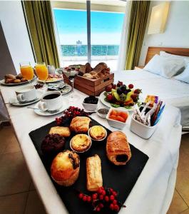 uma mesa de pequeno almoço com pão e outros alimentos numa cama em Monte Gordo Hotel Apartamentos & Spa em Monte Gordo