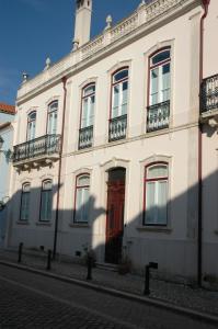 um edifício branco com uma porta vermelha numa rua em Casa da Tia Guida na Golegã