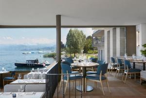 un restaurante con mesas y sillas y vistas al agua en Alex Lake Zürich - Lifestyle hotel and suites, en Thalwil