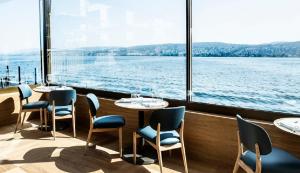 un restaurante con mesas y sillas y vistas al agua en Alex Lake Zürich - Lifestyle hotel and suites, en Thalwil