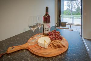 un tavolo con una bottiglia di vino e un piatto di formaggio e bicchieri da vino di Dusky Motels a Te Anau