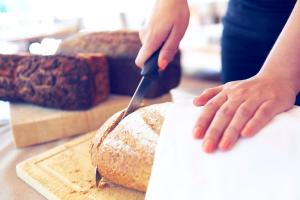 una persona che taglia una pagnotta di pane con un coltello di Aparthotel Delden a Delden