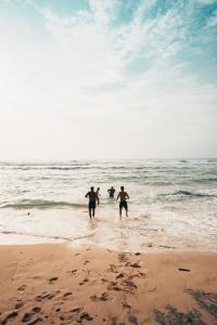 3 Leute laufen im Wasser am Strand in der Unterkunft Piedra Alta Hostel & Suites in La Pedrera