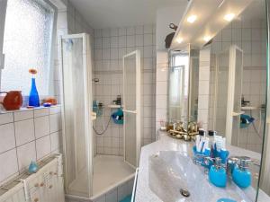 een witte badkamer met een wastafel en een douche bij Baden-BadenSpaApartment in Baden-Baden