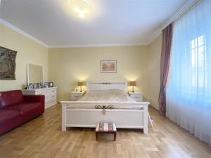 een slaapkamer met een wit bed en een rode bank bij Baden-BadenSpaApartment in Baden-Baden