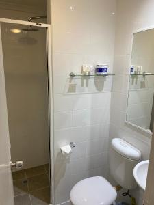 een badkamer met een douche, een toilet en een wastafel bij Silkari Urban CKS Sydney Airport Hotel in Sydney