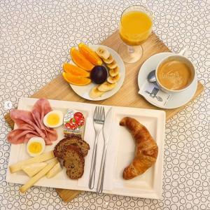 uma mesa com um prato de comida para o pequeno-almoço e uma chávena de café em Hotel Les Arcades em Genebra