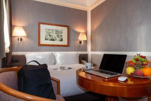 ein Hotelzimmer mit einem Schreibtisch und einem Laptop darauf in der Unterkunft Grand Hotel Ortigia in Syrakus