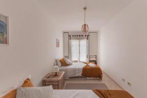 ein weißes Schlafzimmer mit 2 Betten und einem Fenster in der Unterkunft Zambujeira do Mar 4-Bed House Perfect for Families & Friends in Zambujeira do Mar