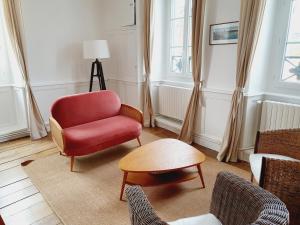 een woonkamer met een rode stoel en een tafel bij Les Sablons - Très Bel Appartement , Lumineux in Saint-Malo