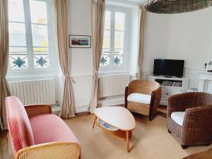 een woonkamer met stoelen en een tafel en een televisie bij Les Sablons - Très Bel Appartement , Lumineux in Saint-Malo