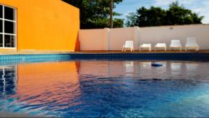 een zwembad met stoelen en water voor een gebouw bij Villa Solarium Pousada in Cabo Frio