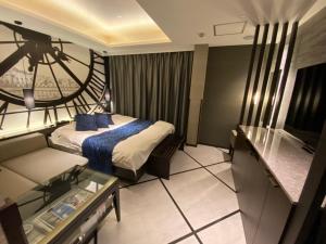 Habitación de hotel con cama y sofá en ホテル ポルト 男塾ホテルグループ, en Himeji