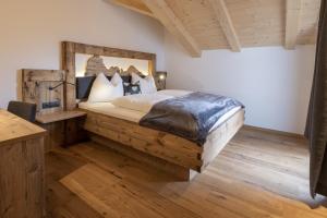 ein Schlafzimmer mit einem großen Bett mit einem Holzrahmen in der Unterkunft Platiederhof in Lajen