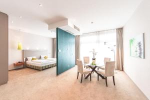 Cette chambre comprend une table, des chaises et un lit. dans l'établissement PLAZA Hotel Hanau, à Hanau