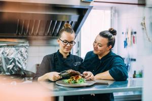 zwei Frauen stehen in einer Küche mit einem Teller Essen in der Unterkunft Guesthouse Mimbelli in Orebić