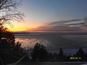 un coucher de soleil sur une masse d'eau dans l'établissement Gîte Au Perchoir, à Baie-Saint-Paul