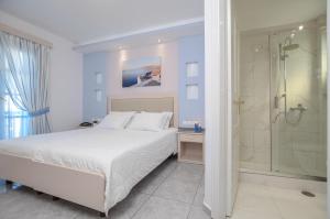 una camera bianca con letto e doccia di Ilion Hotel a Naxos Chora