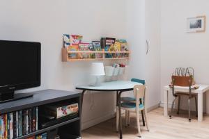 een woonkamer met een tafel en stoelen en een televisie bij Zus of So in Oostende