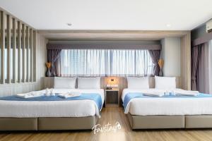 two beds in a hotel room with windows at So Boutique Jomtien Beach Pattaya in Jomtien Beach