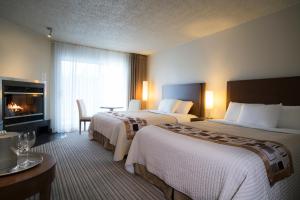 a hotel room with two beds and a fireplace at Excelsior Hôtel Spa Sainte-Adèle in Sainte-Adèle