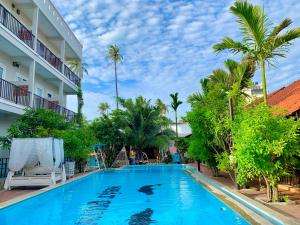 uma piscina em frente a um hotel com palmeiras em MAY Bungalow em Mui Ne