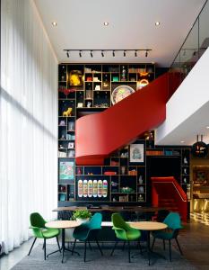 um restaurante com mesas e cadeiras e uma escada vermelha em citizenM Washington DC Capitol em Washington