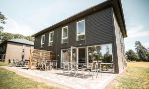 a black house with chairs and tables on a patio at Saxnäs Ferieboende L. Erik in Färjestaden