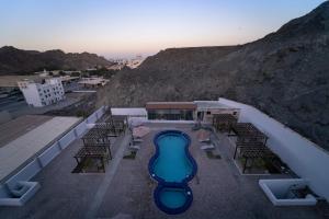 a view of a pool with chairs and a mountain at Riyam Hotel in Muscat