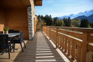 una terraza de madera con mesa, sillas y montañas en Le Mazot d'la Marmotte T3, en Passy