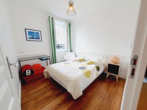 een slaapkamer met een bed met witte lakens en houten vloeren bij Les Sablons - Très Bel Appartement , Lumineux in Saint-Malo