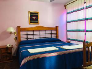 ein Schlafzimmer mit einem blauen Bett mit zwei Handtüchern darauf in der Unterkunft Hotel Cazomalli Oaxaca in Oaxaca de Juárez