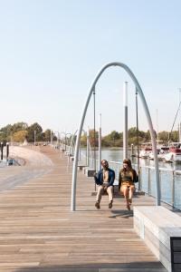 two people sitting on a boardwalk next to the water at InterContinental - Washington D.C. - The Wharf, an IHG Hotel in Washington