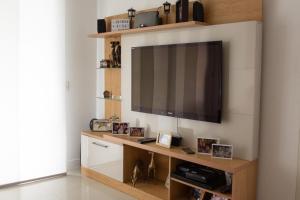 sala de estar con TV de pantalla plana en la pared en QUARTO EM CONDOMINIO DE LUXO NA BARRA DA TIJUCA, en Río de Janeiro