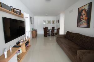 sala de estar con sofá y TV de pantalla plana en QUARTO EM CONDOMINIO DE LUXO NA BARRA DA TIJUCA, en Río de Janeiro