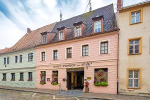 un grand bâtiment rose avec des fleurs aux fenêtres dans l'établissement Hotel-Pension zum Markt, à Torgau