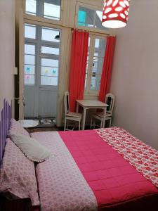 - une chambre avec un lit rose, une table et une fenêtre dans l'établissement Casa Capilla, à Valparaíso